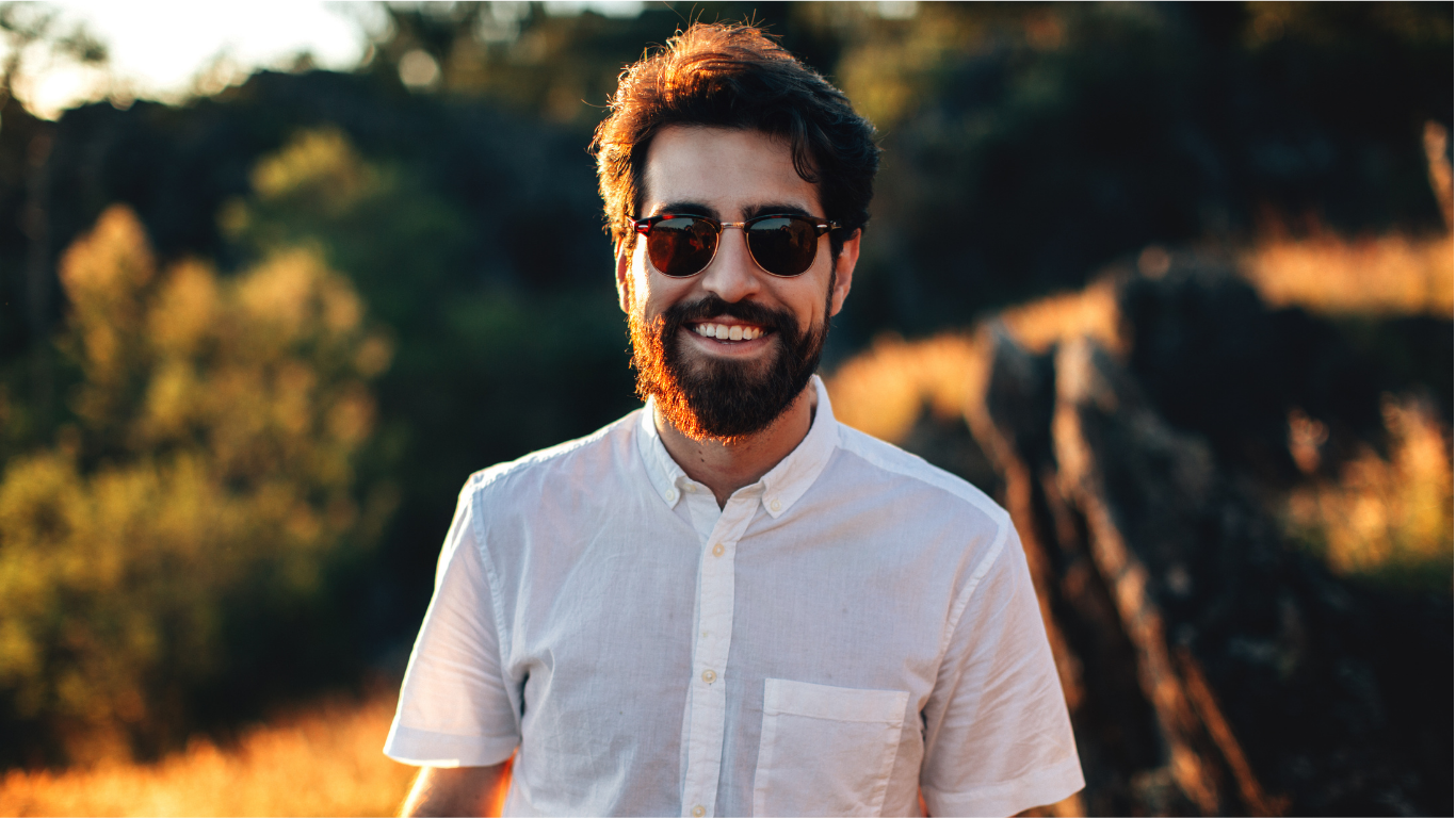 Sonnenbrille Mann mit Bart und Sonnenbrille lächelt im Freien bei Sonnenlicht.