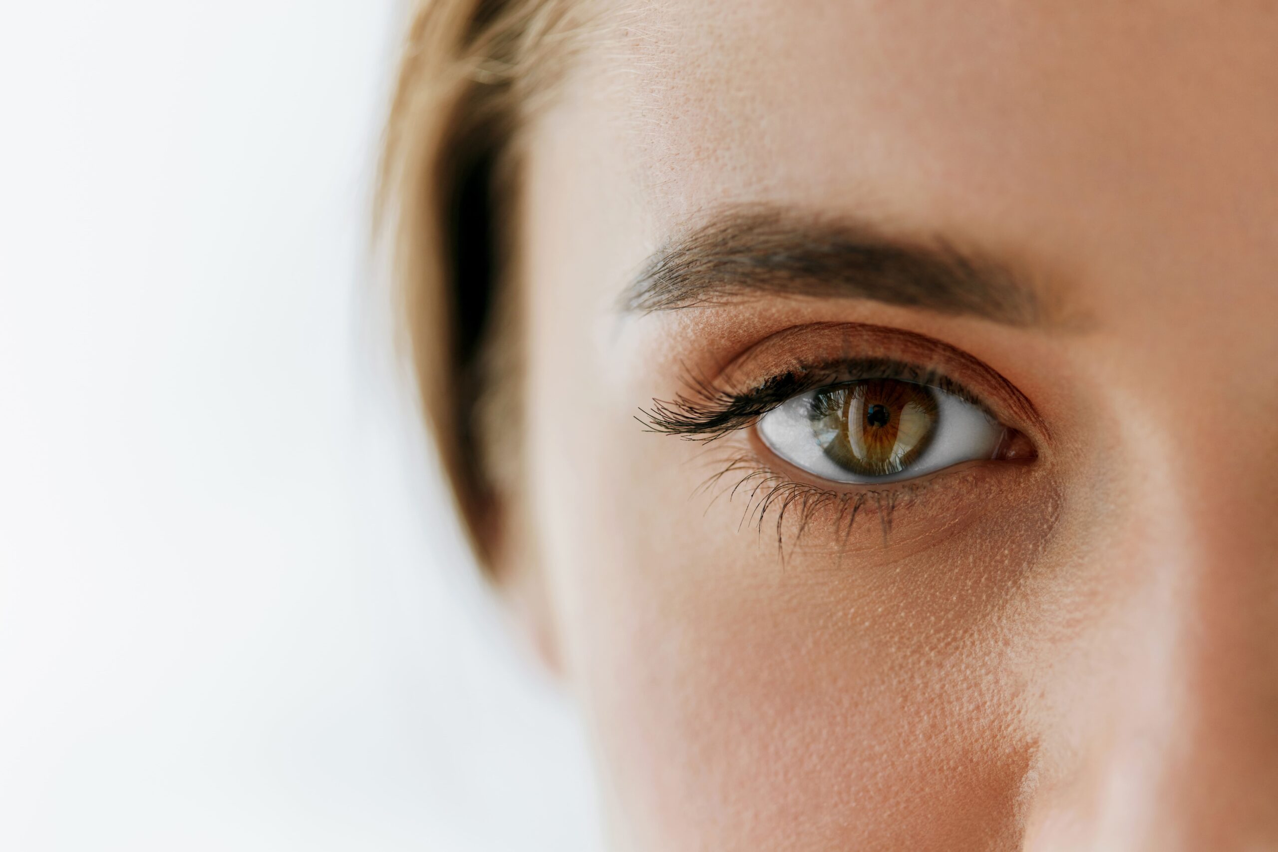 Gesunde Augen durch professionelles Screening Nahaufnahme eines weiblichen Gesichts mit Fokus auf das braune Auge und die Augenbraue.