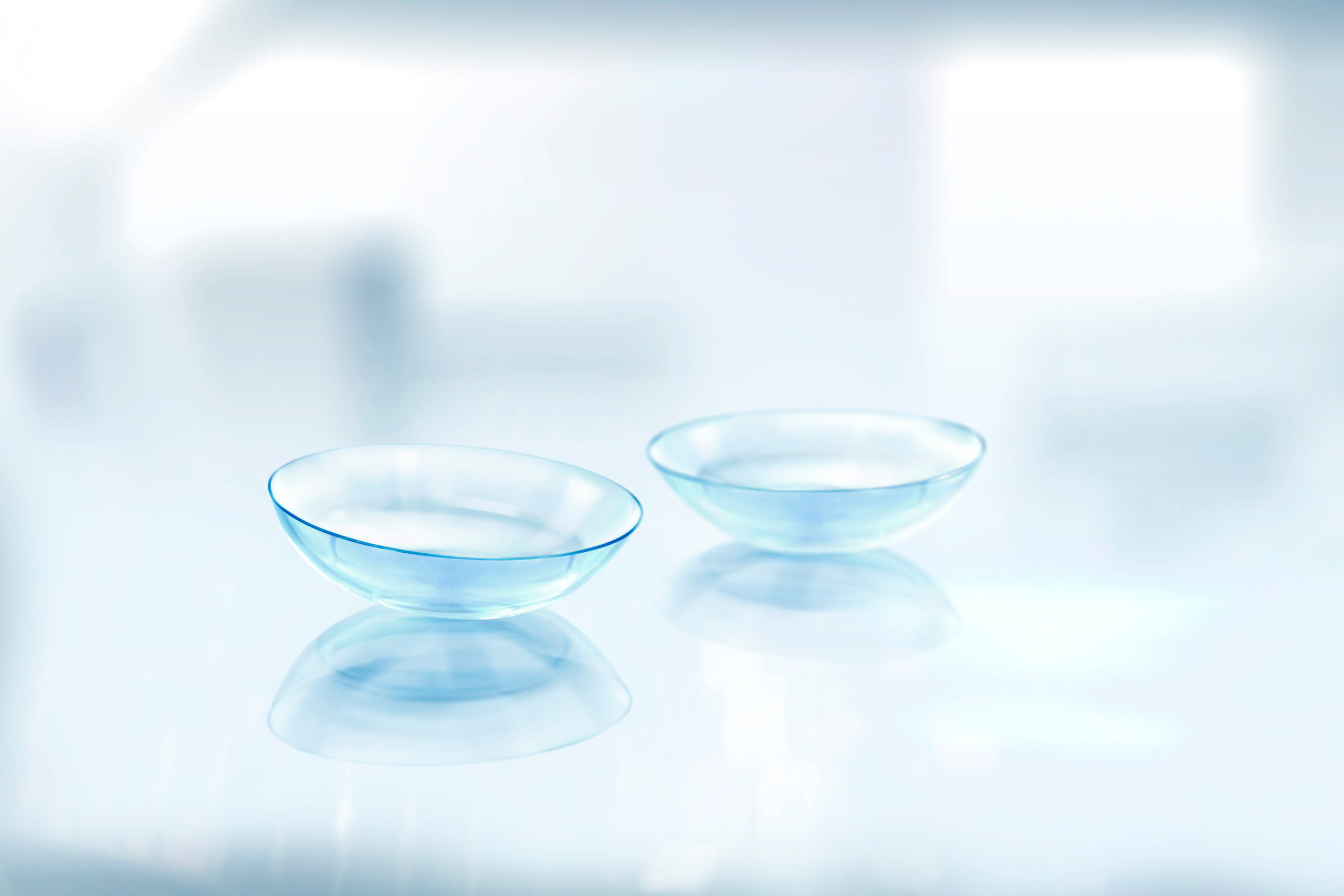 Kontaktlinsen Zwei transparente Kontaktlinsen liegen auf einer reflektierenden weißen Oberfläche