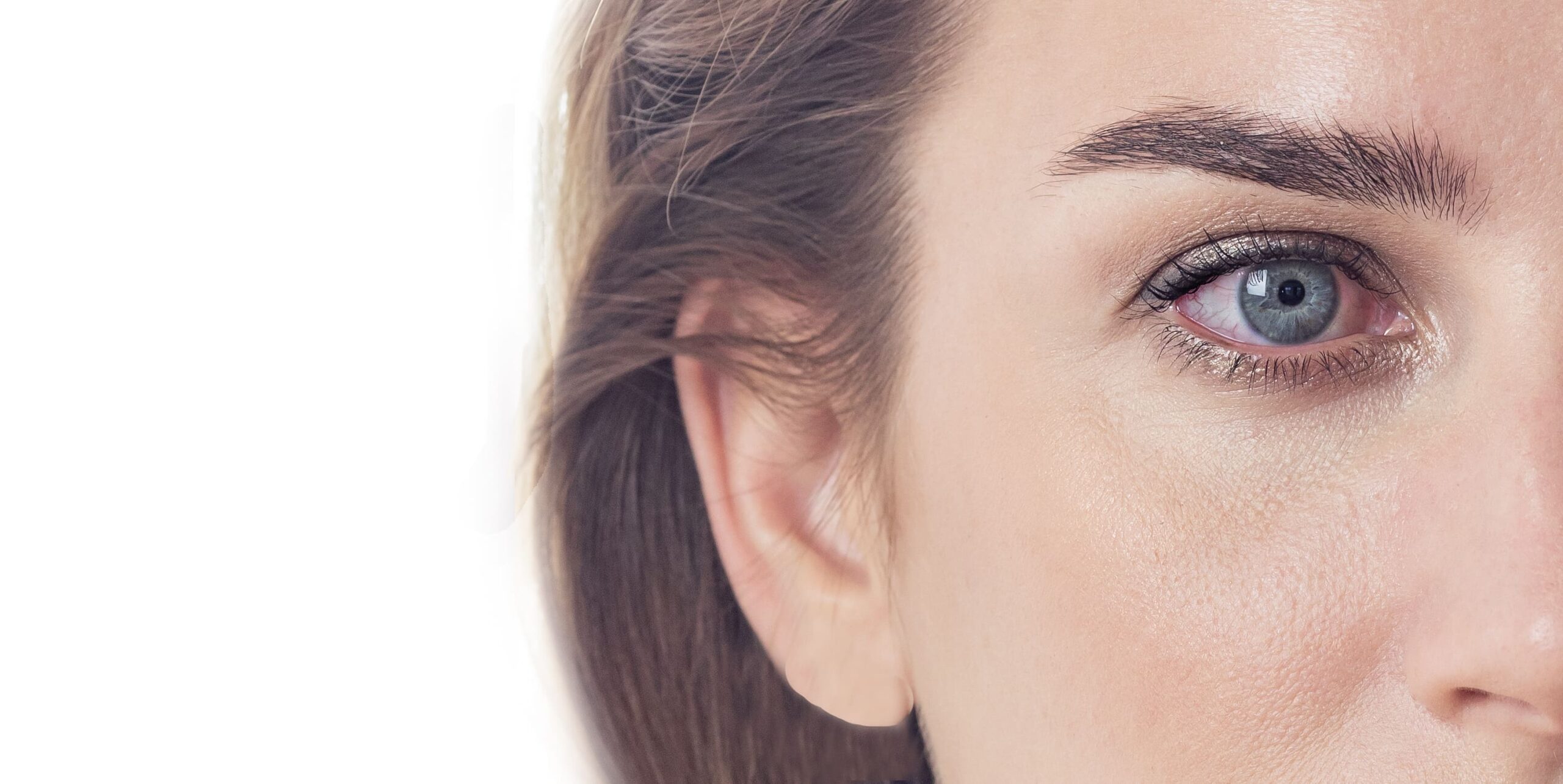 Für wen sind Sklerallinsen geeignet? Nahaufnahme der rechten Gesichtshälfte einer Frau mit blauen Augen und braunen Haaren.